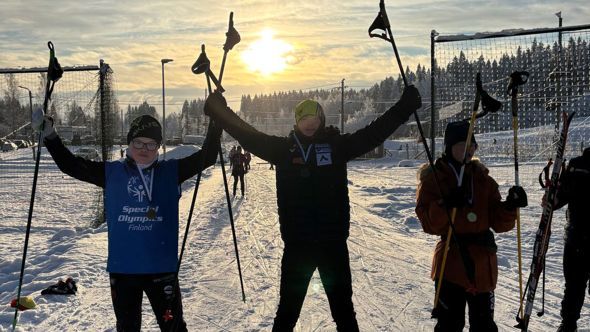 SO-hiihtäjät Elmeri, Eino ja Osmo poseeraamassa kameralle talvisessa aurinkolaskumaisemassa. Päällä hiihtovarusteet.